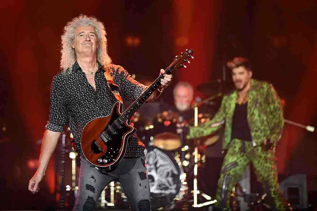 Brian May in primo piano sullo sfondo dei Queen 3.0